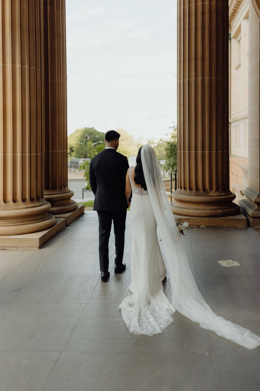 Bride and Groom at a city wedding. Bride wearing a floor-length simple and classic tulle veil