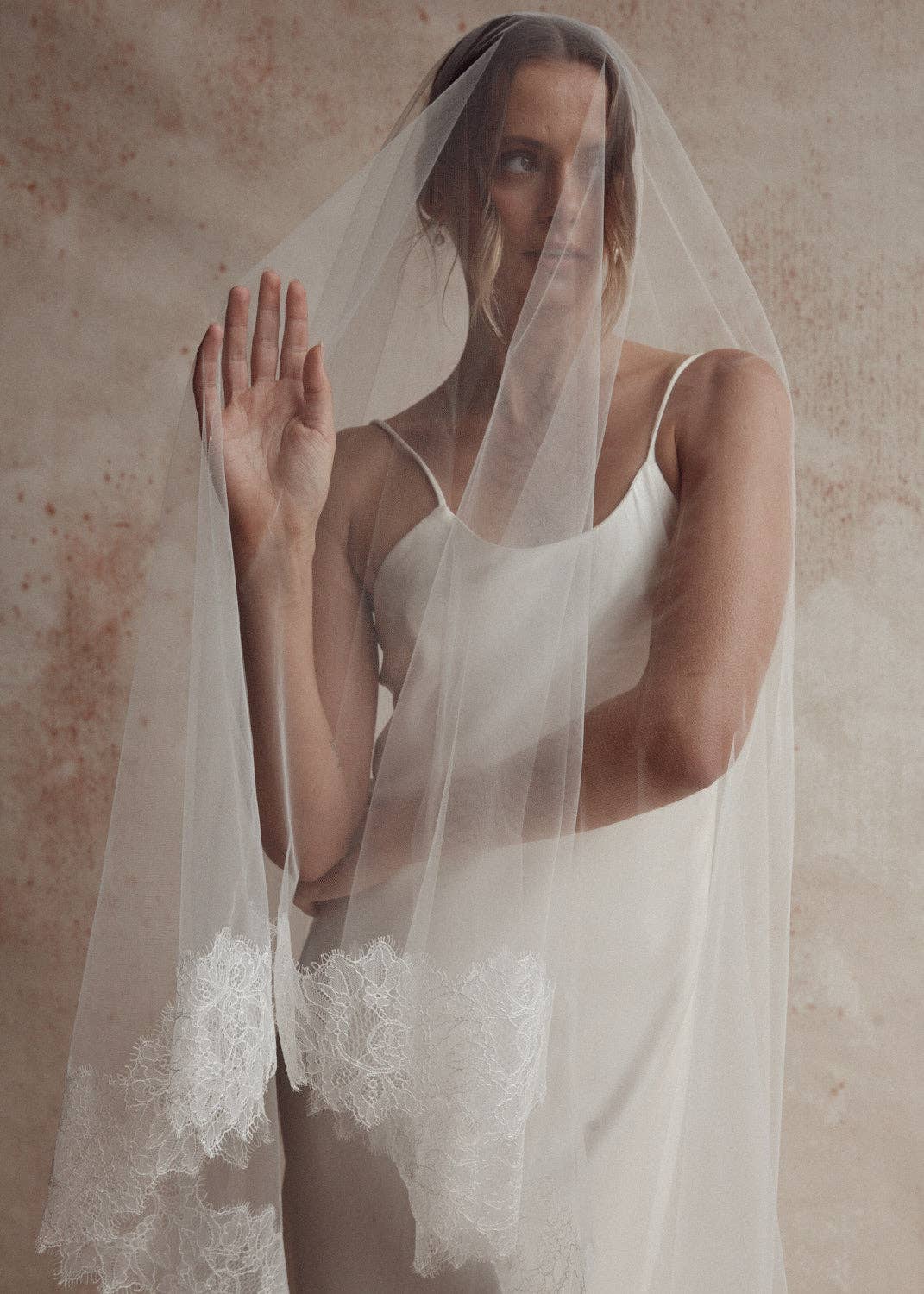 Bride underneath a bridal blusher veil with lace trimmed edges